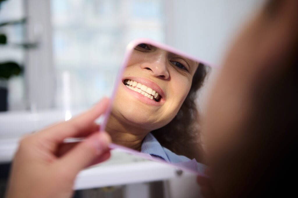 Female looking at teeth in mirror